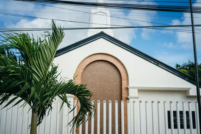 Low angle view of palm tree by building against sky