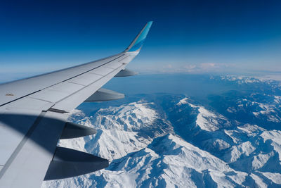 Aerial view of snowcapped mountains against blue sky