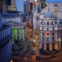 High angle view of cars on road by buildings in city at dusk