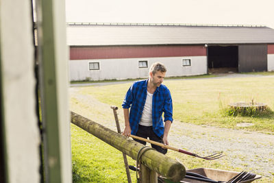 Farmer arranging equipment outside barn at farm