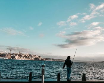 Man fishing in sea against sky