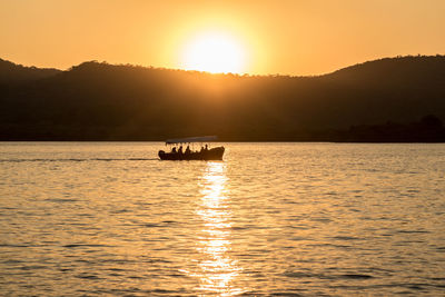 Silhouette boat sailing on sea against sky during sunset