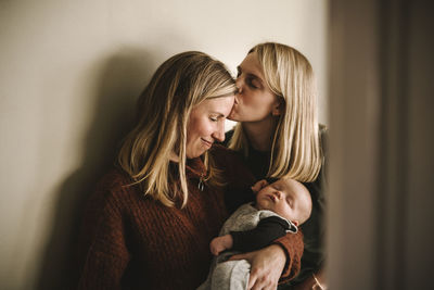 Mothers kissing and holding sleeping newborn baby