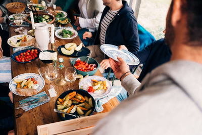 Cropped image of man passing plate to friend during lunch party