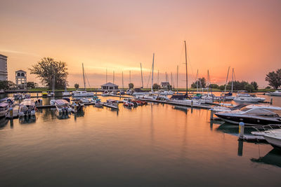 Boats moored at harbor against sky during sunset