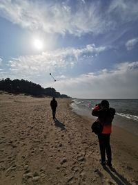 Rear view of people on beach against sky