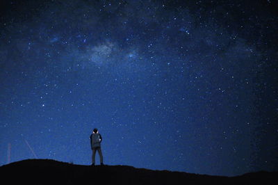 Rear view of man standing against star field at night