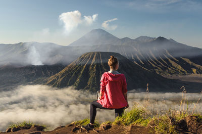 Woman sitting on land against mountain range