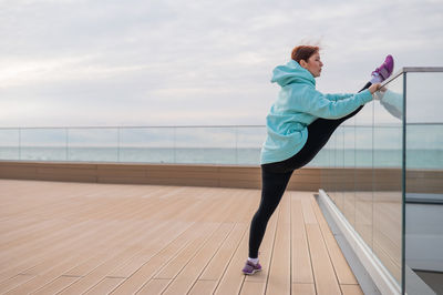 Full length of young woman exercising on floor