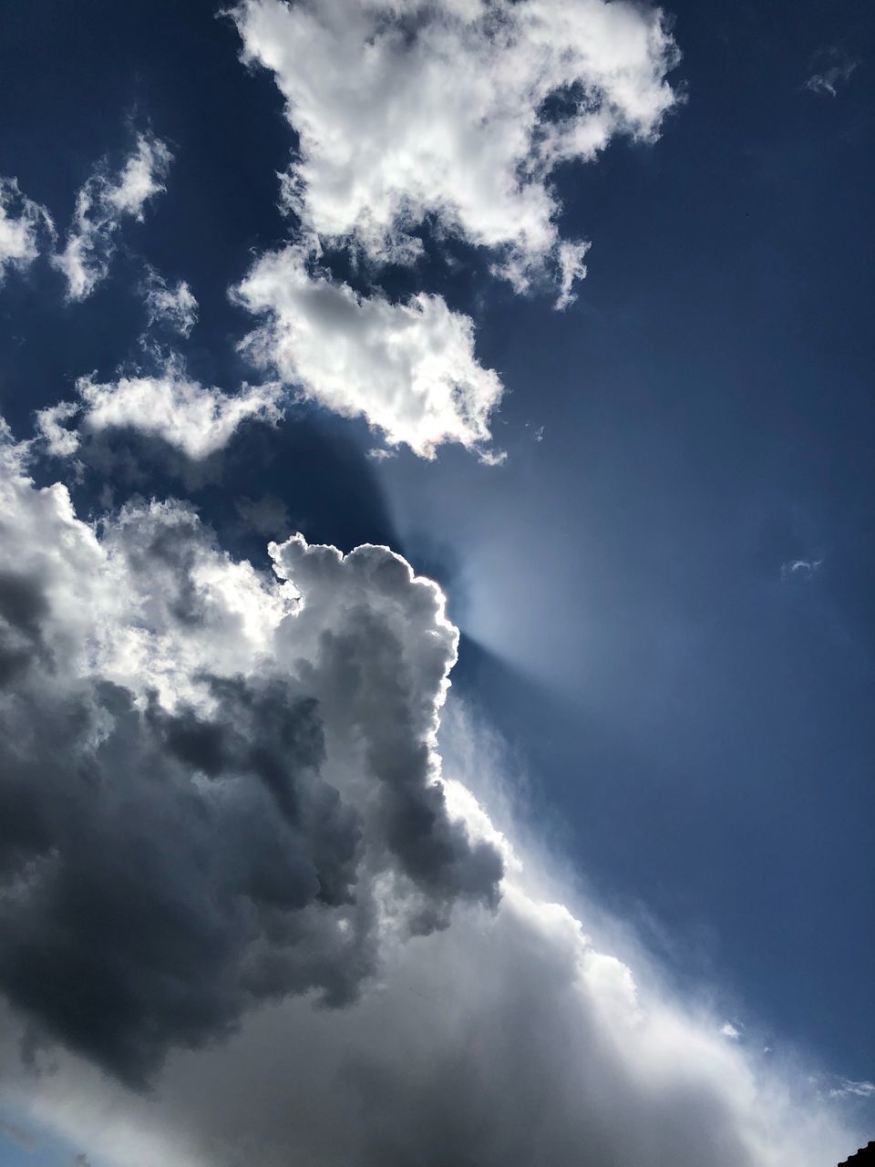 LOW ANGLE VIEW OF SUN STREAMING THROUGH CLOUDS IN SKY