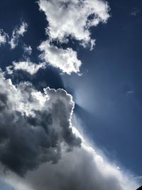 Low angle view of sunlight streaming through clouds