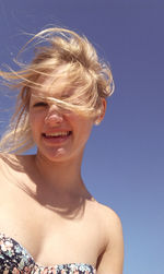 Portrait of smiling beautiful woman against clear blue sky