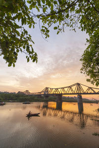 Man sailing in river against sky during sunset