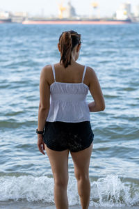 Rear view of woman standing by sea