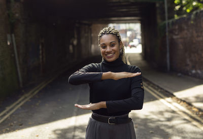 Portrait of woman gesturing while standing on footpath