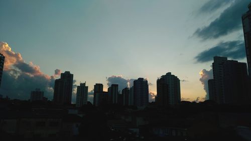 Modern buildings in city against sky during sunset