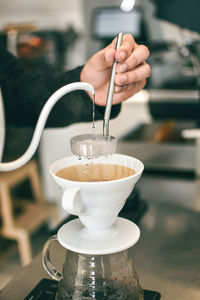 Cropped hand of woman preparing coffee at cafe