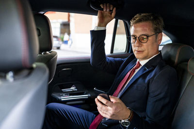 Businessman using smart phone sitting in car