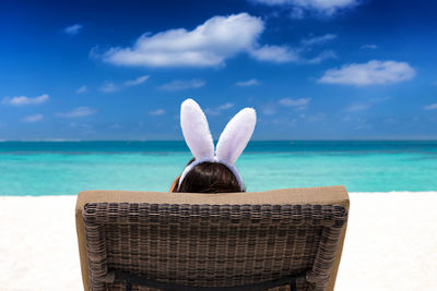 Rear view of woman wearing rabbit ears headband at beach