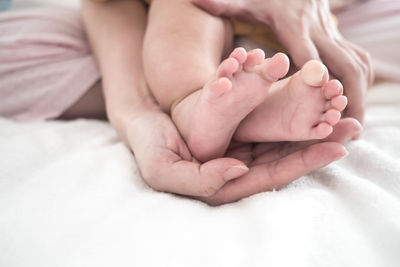 Low section of baby lying on bed