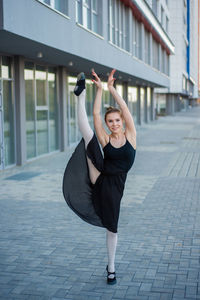 Full length portrait of young woman standing in city