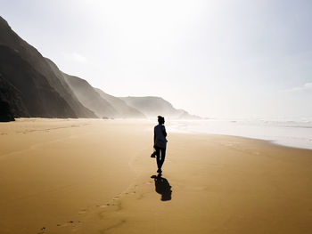 Woman walking by seashore at beach on sunny day