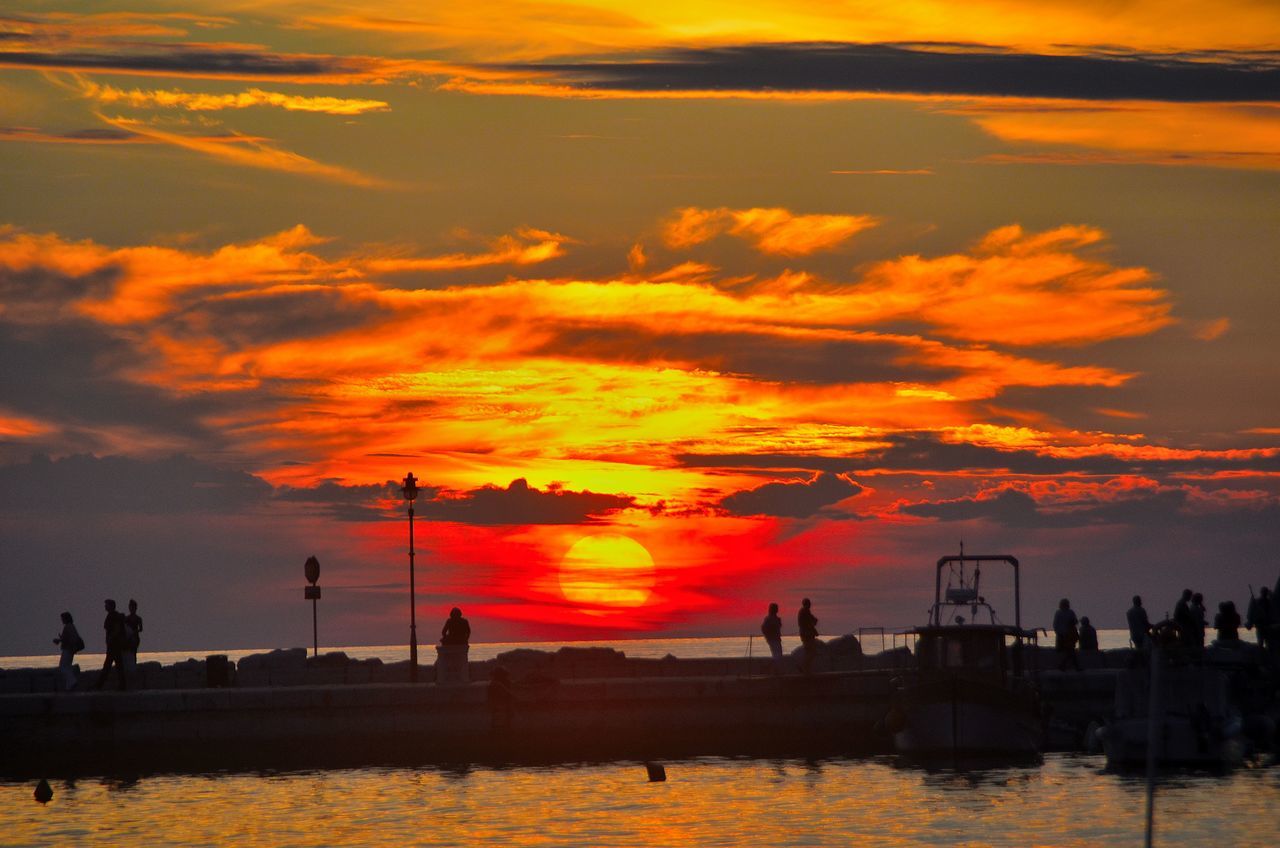 sunset, water, sea, orange color, sky, silhouette, scenics, beauty in nature, large group of people, sun, leisure activity, tranquil scene, cloud - sky, lifestyles, waterfront, beach, tranquility, horizon over water, idyllic