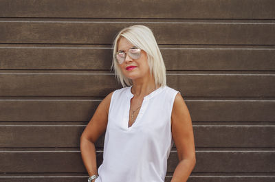 Portrait of blonde in sunglasses on background of brown blinds shutters garage house