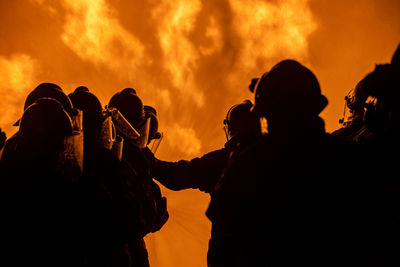 Silhouette firefighters spraying water on fire
