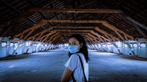 Portrait of woman wearing face mask standing in empty warehouse