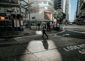 People walking on street against buildings in city