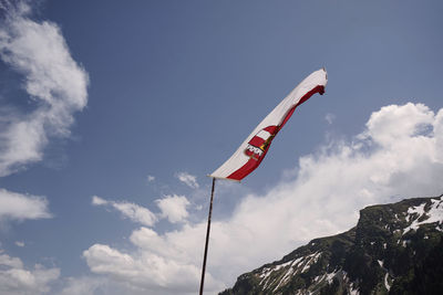 Low angle view of flag on mountain against sky