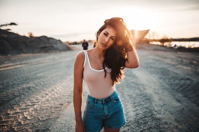 Portrait of young woman standing on land against sky