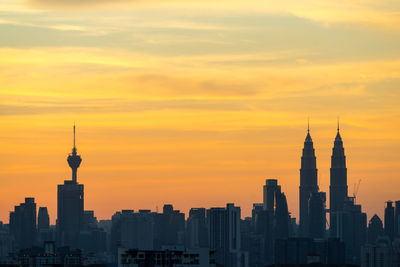 Petronas towers and kuala lumpur tower against sky during sunset