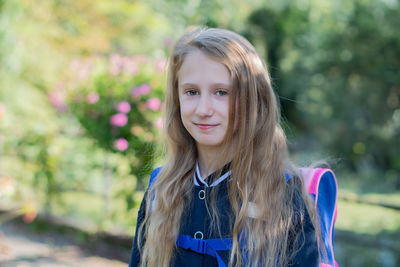 Back to school, portrait of a little girl from primary school outdoors, enjoying flowers in a