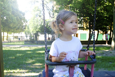 Cute girl sitting on swing at playground