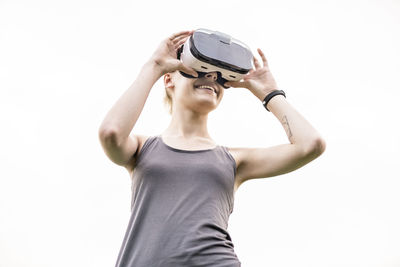 Smiling young woman using virtual reality glasses outdoors