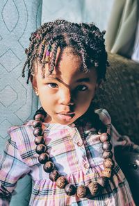 Close-up portrait of cute baby girl wearing necklace at home