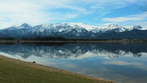 Scenic view of lake by snowcapped mountains against sky