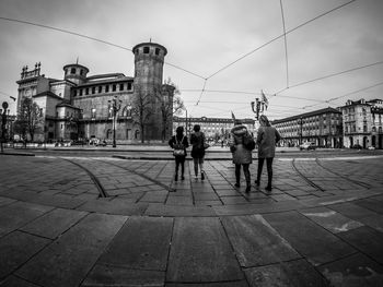 People walking on street in city against sky