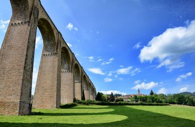 Low angle view of arch bridge against sky on sunny day