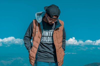 Young man standing against sky