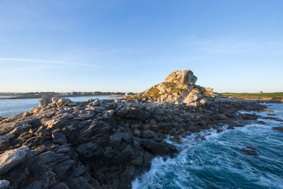 Rock formation on beach against sky