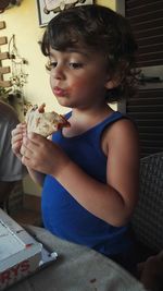 Girl eating pizza while standing by table at home