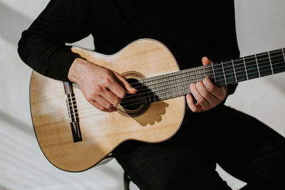 Midsection of man playing classical guitar