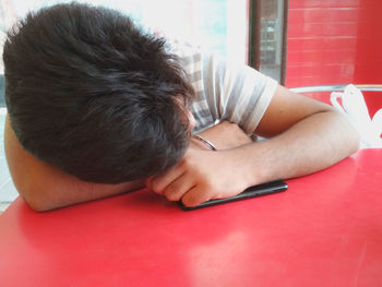 Close-up of teenage boy leaning on red table