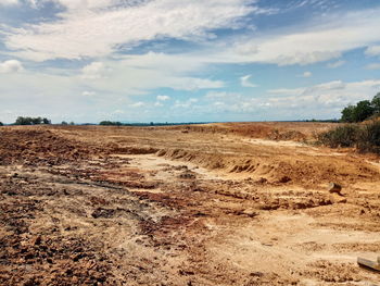 Dirt road on field against sky