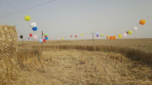 Low angle view of balloons flying over field against sky