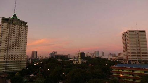 Buildings in city against sky at sunset