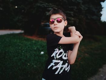 Boy wearing sunglasses standing against plants outdoors